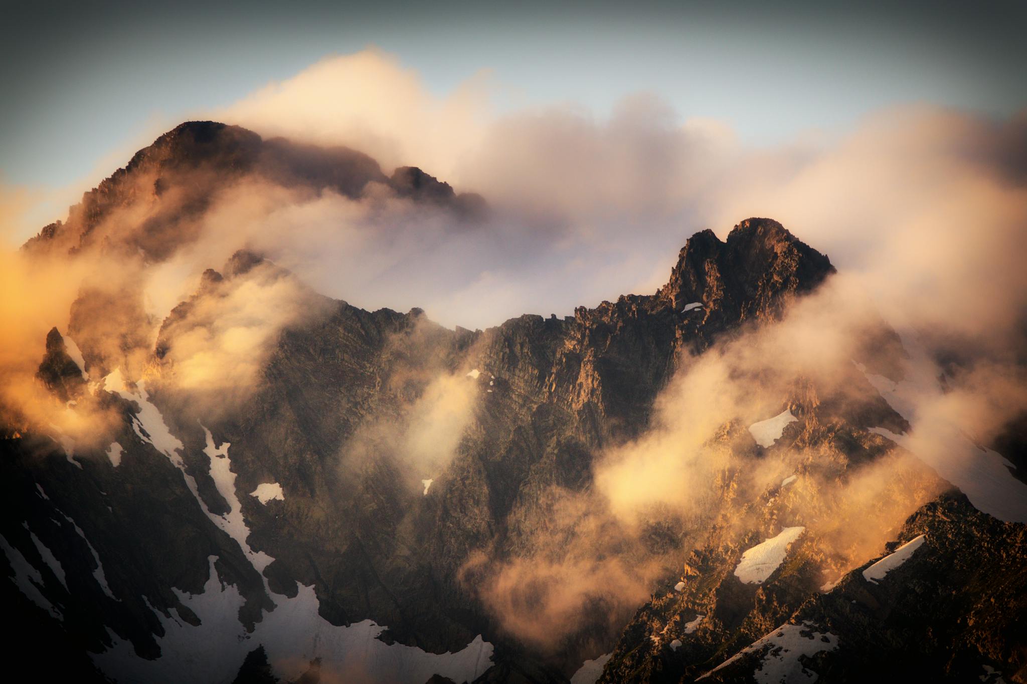 Sunlit peaks and clouds create a dramatic scene in Красная Поляна mountains.